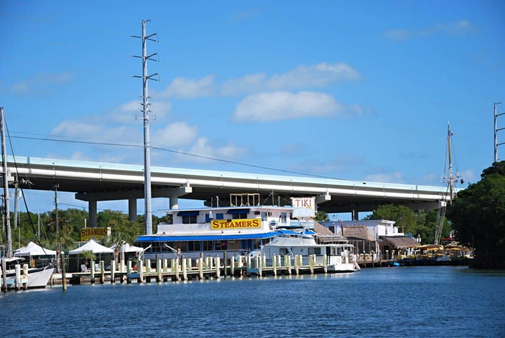 key Largo waterfront dining scene with boats docked alongside a tiki bar, offering a laid-back atmosphere for babymooners to enjoy.