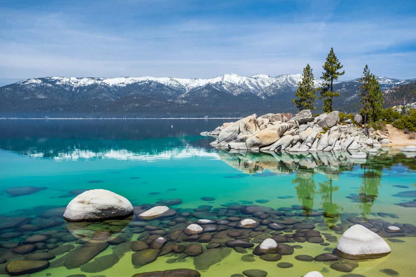 The crystal-clear waters of Lake Tahoe with snow-capped mountains in the background, offering a serene babymoon destination in California