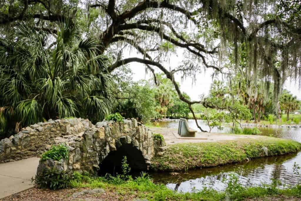 A peaceful park in New Orleans with a quaint stone bridge and lush surroundings, offering a serene walk for babymooners