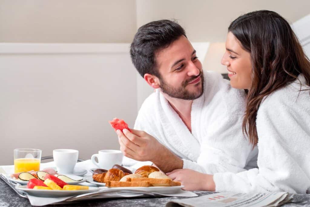 A couple enjoying room service breakfast in a hotel, savoring their babymoon