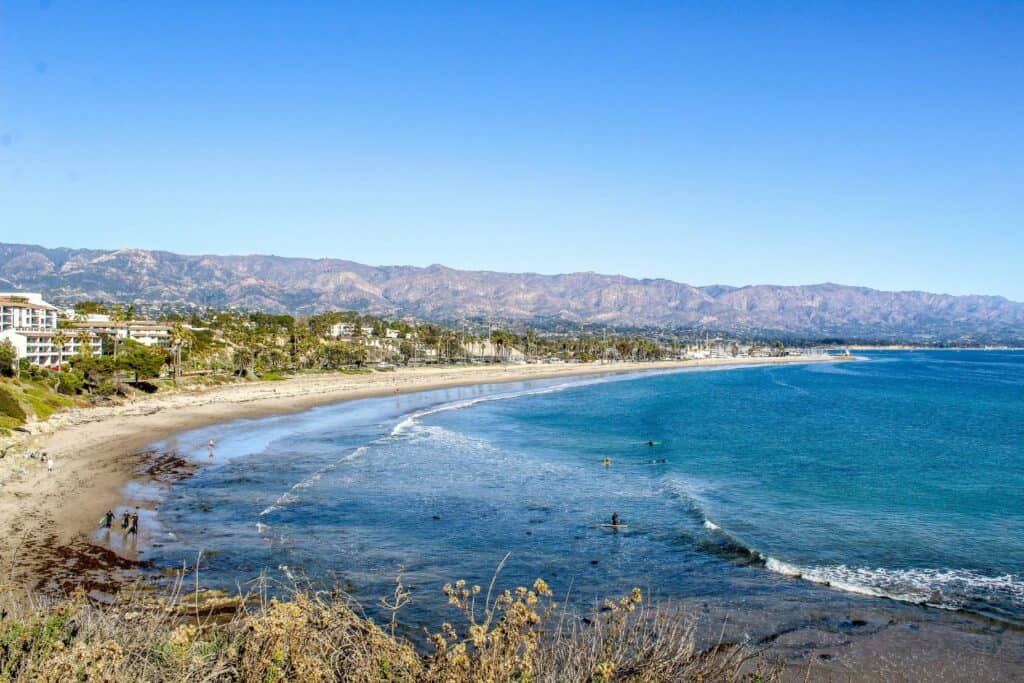 The scenic coastline of Santa Barbara with palm trees and distant mountains, a picturesque setting for the best babymoon locations in California