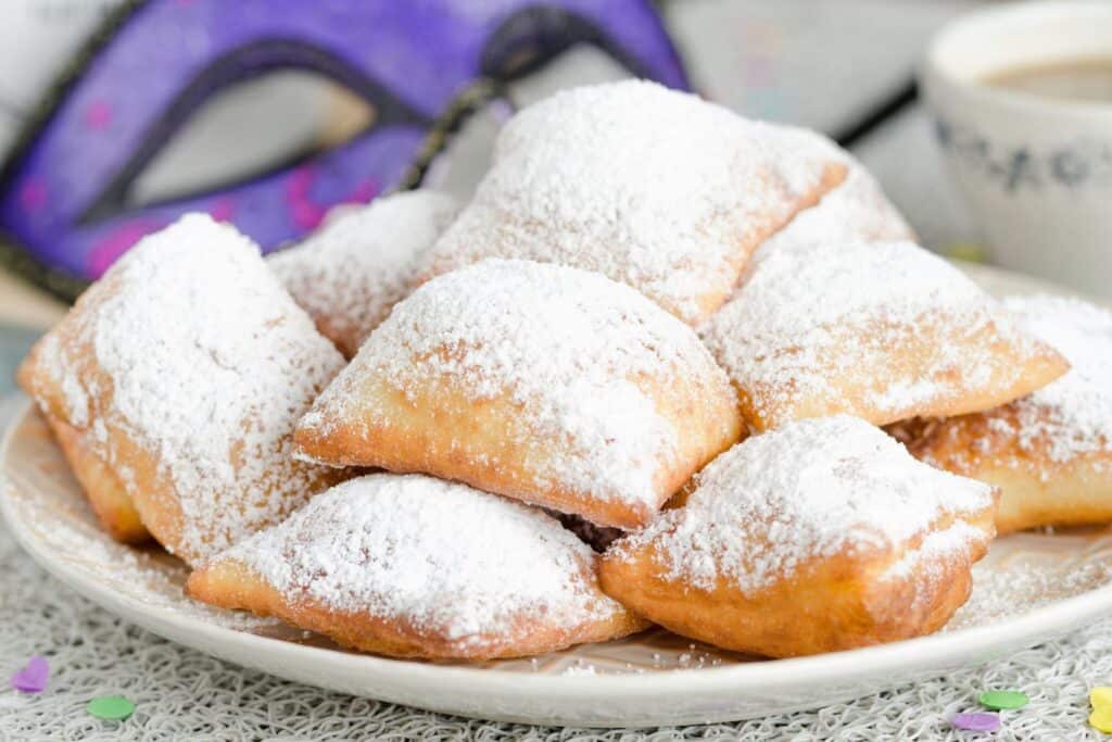 A plate of freshly made beignets heavily dusted with powdered sugar, a sweet treat for parents-to-be enjoying a babymoon in New Orleans