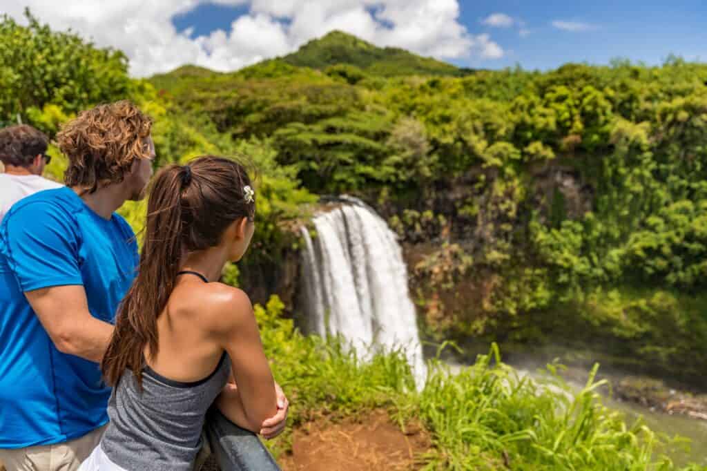 A couple overlooking a waterfall in Kauai after a relaxing hike