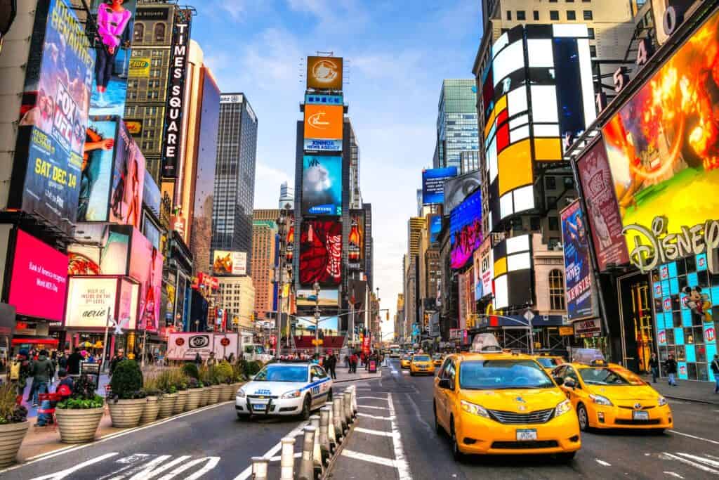 Yelllow taxis and busy cars in the middle of time quare New York City on a blue bird day