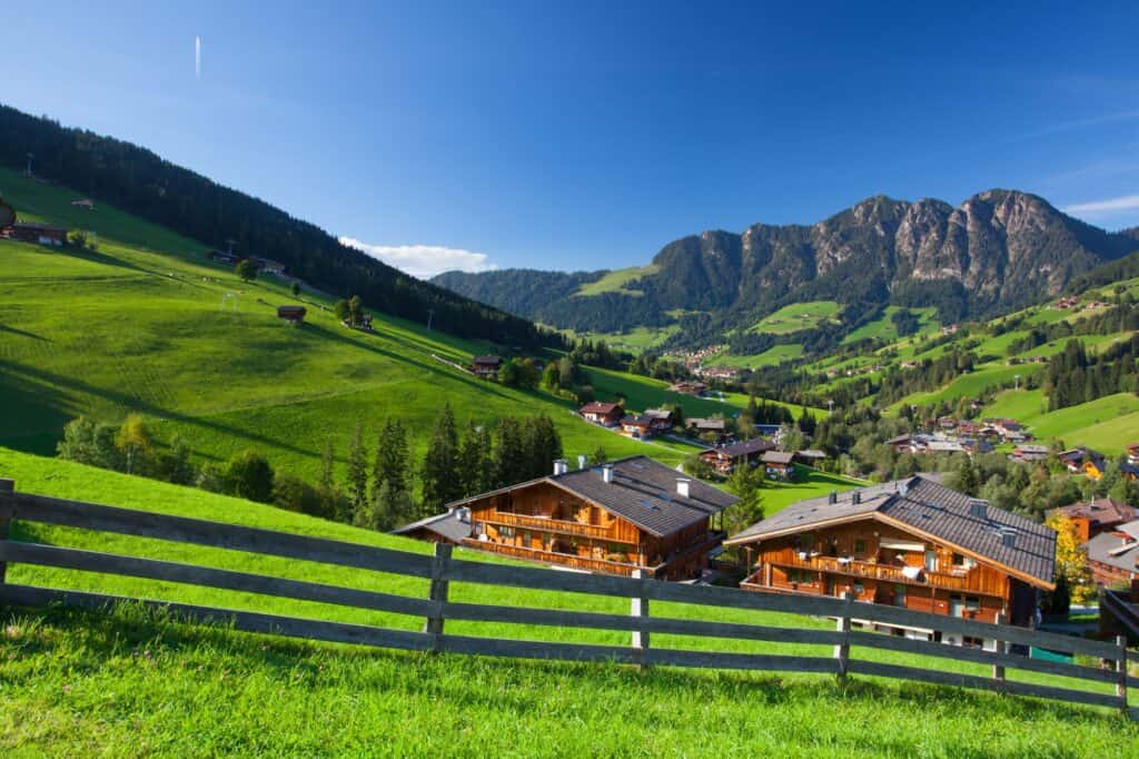 Lush green grass mountains on the coutryside of Austria with wooden houses lining the hills