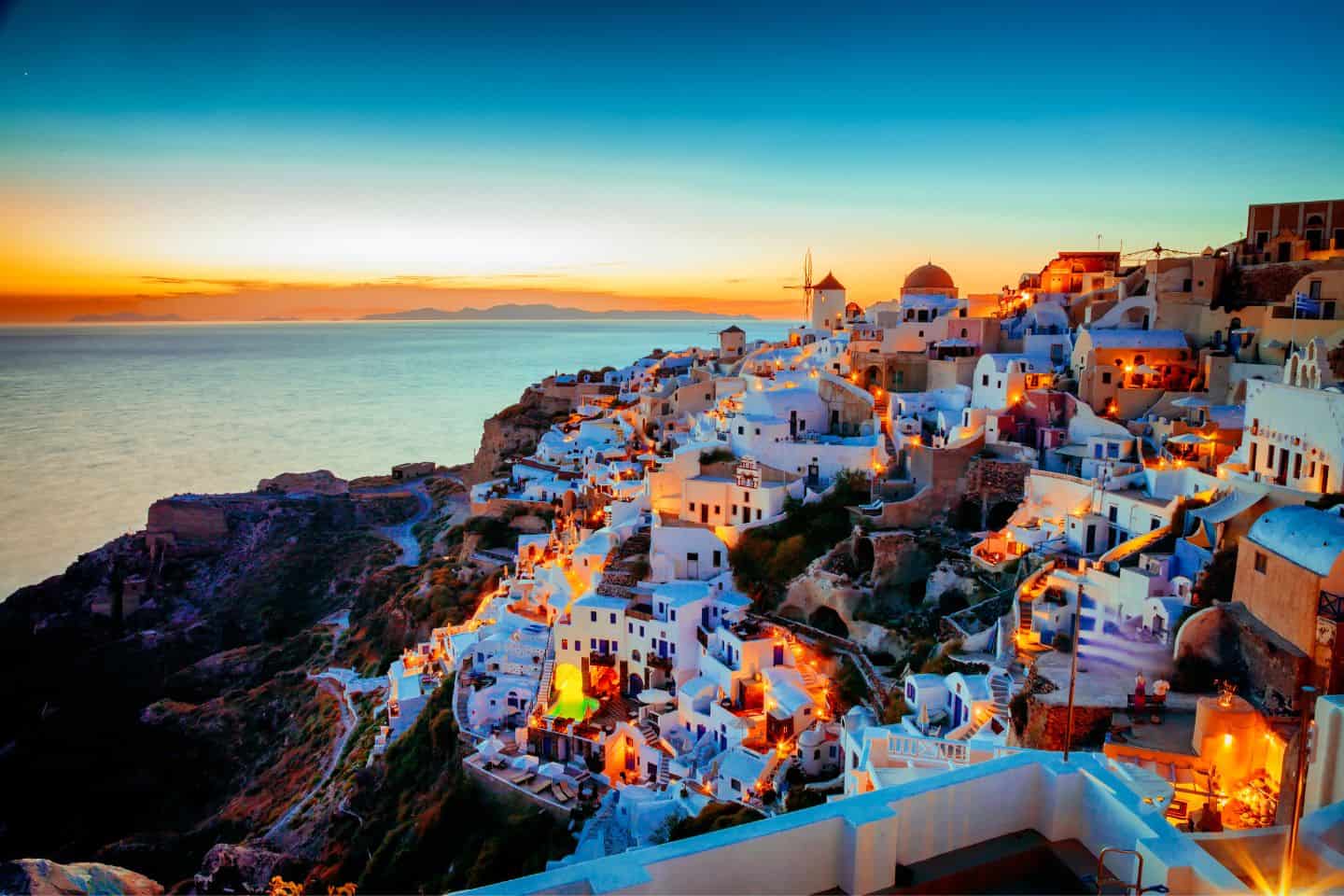 Santorini at sunset with the white houses all light up by the golden hughes of the sunset