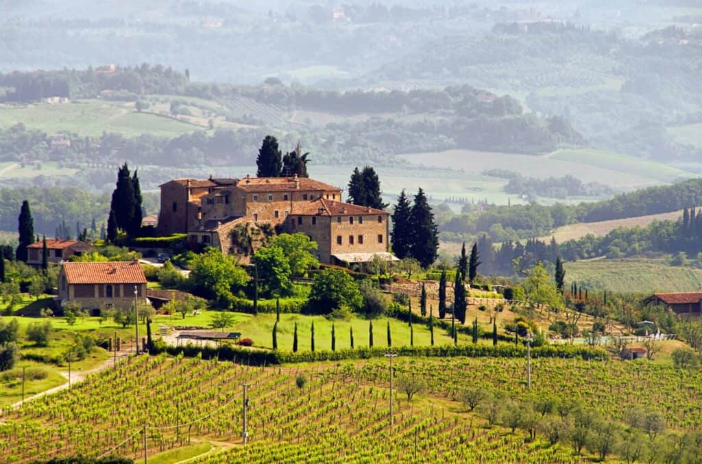 Vineyards on rolling hills in Tuscany Italy with an old brick mansion in the background