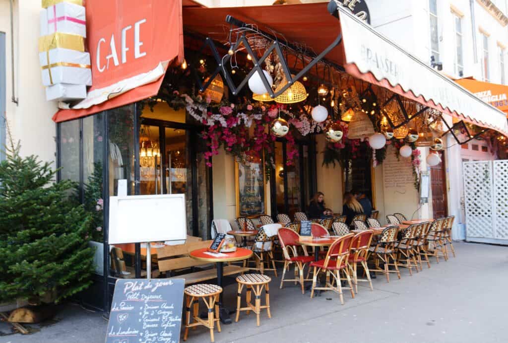 A street cafe in Paris with red chairs, wodden tables and a chalk board sign out front